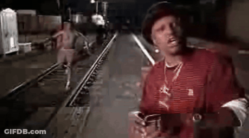 Man In Red Shirt And Hat On Train Track At Night GIF