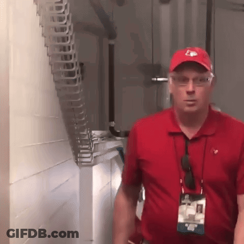 Man In Red Shirt And Red Hat With Letter E Standing In Hallway GIF