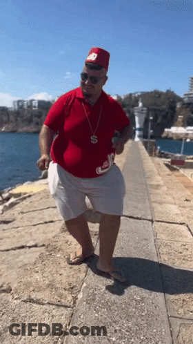 Man In Red Shirt And White Shorts With S Necklace GIF