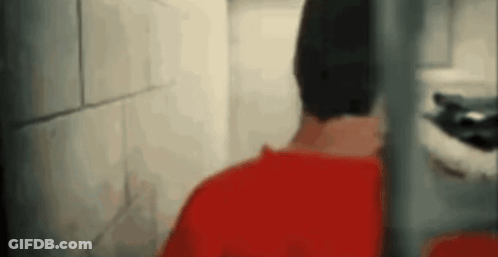 Man In Red Shirt Behind Fence GIF