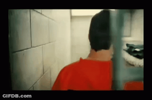 Man In Red Shirt Behind Prison Cell Fence GIF