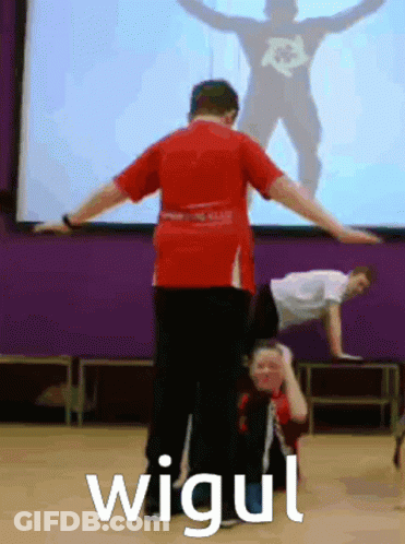 Man In Red Shirt Doing Handstand In Front Of Screen Saying Wigui GIF
