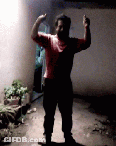 Man In Red Shirt Flexing Muscles In Dark Room GIF