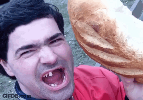 Man In Red Shirt Holding Loaf Over Head GIF