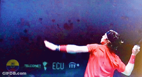 Man In Red Shirt Holding Tennis Racquet In Front Of ECU ITF Sign GIF