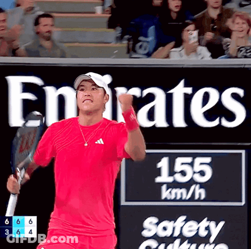 Man In Red Shirt Holding Tennis Racquet In Front Of Emirates Sign GIF