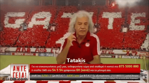Man In Red Shirt In Front Of Tatakis Banner GIF