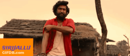 Man In Red Shirt In Front Of Thatched Building Saying Siriallu GIF