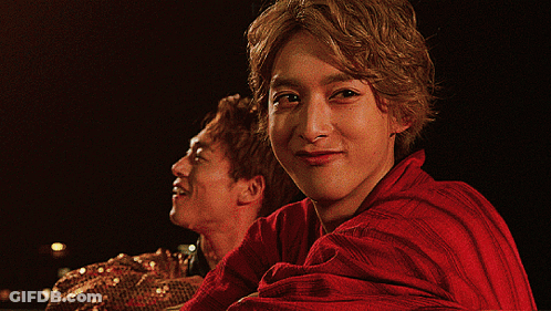Man In Red Shirt Looking At Camera With Another Man Behind GIF