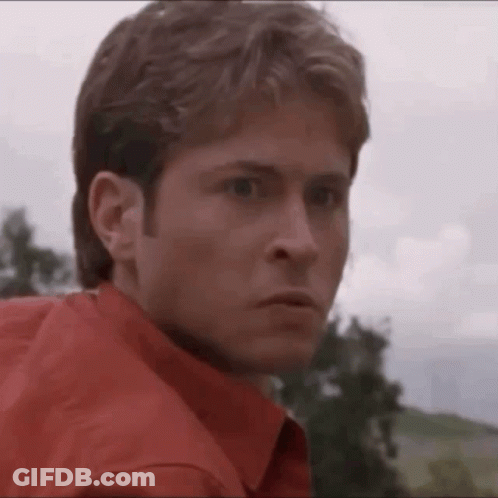 Man In Red Shirt Looking At Camera With Trees GIF