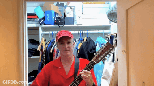 Man In Red Shirt Playing Guitar In Closet With Flybridge Box GIF