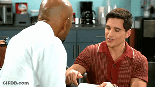 Man In Red Shirt Pointing And Talking To Man In White Shirt GIF