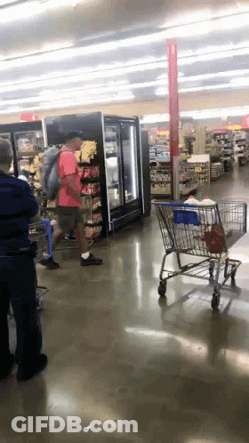 Man In Red Shirt Pushing Shopping Cart GIF