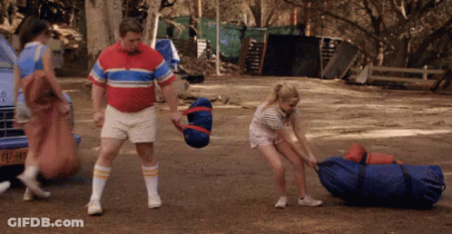 Man In Red Shirt Pushing Woman Pulling Bag GIF