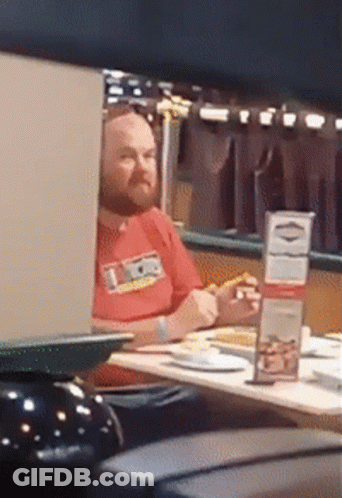 Man In Red Shirt Saying Ice Sitting At Table GIF