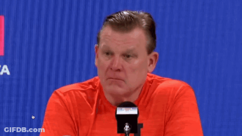 Man In Red Shirt Sitting At Microphone Looking At Camera GIF