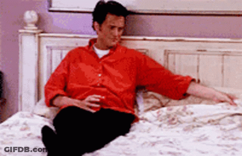 Man In Red Shirt Sitting On Bed Holding Beer GIF