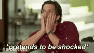 Man In Red Shirt Sitting On Couch With Hands On Face GIF