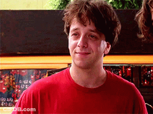 Man In Red Shirt Smiling In Front Of Coca Cola Sign GIF