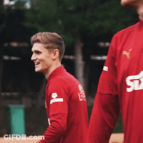 Man In Red Shirt Smiling With Dam On Sleeve GIF