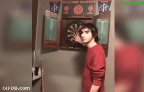 Man In Red Shirt Standing Before Dart Board GIF