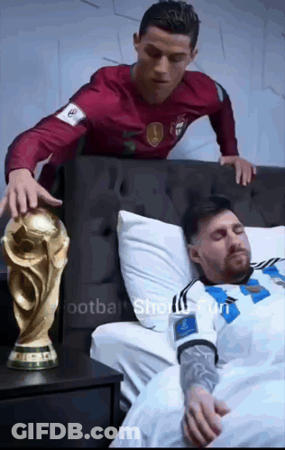 Man In Red Shirt Standing Next To Man In White Shirt In Bed GIF