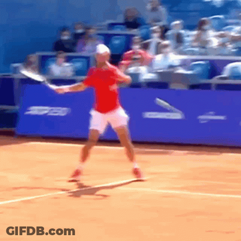Man In Red Shirt Swinging Tennis Racquet On Court GIF