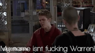 Man In Red Shirt Talking To Another Man In Front Of TV Saying My Name Isn't Fucking Warren GIF