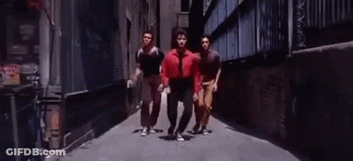 Man In Red Shirt Walking Down Alley With Two Men GIF