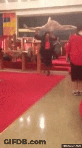 Man In Red Shirt Walking Down Hallway With Red Carpet GIF