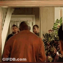 Man In Red Shirt Walking Through Doorway With Group GIF