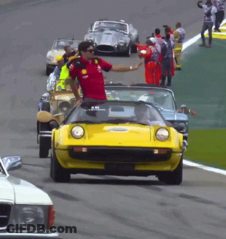Man In Red Shirt Waves To Yellow Car On Track GIF