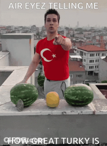 Man In Red Shirt With Turkish Flag Points At Two Watermelons GIF