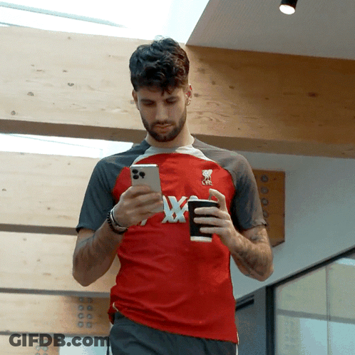 Man In Red Shirt With X Looking At Phone GIF