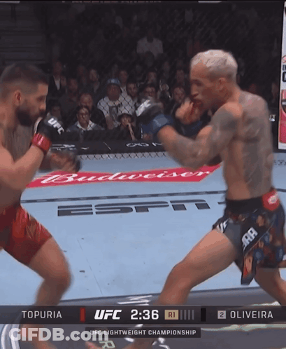 Man In Red Shorts Beside Man Lying In Cage GIF