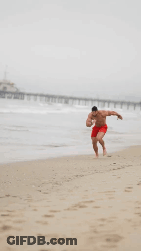 Man In Red Shorts Running On Beach GIF