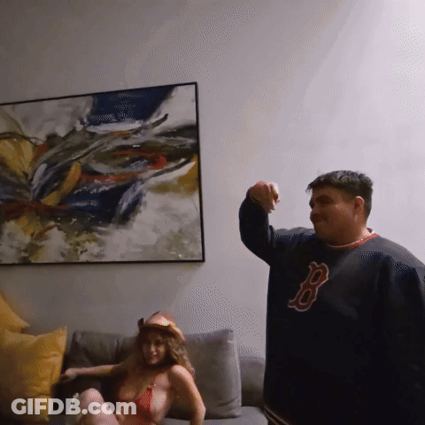 Man In Red Sox Jersey Beside Bikini Woman On Couch GIF