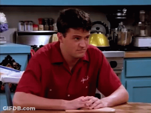 Man In Red Spice Shirt Sits At Table GIF