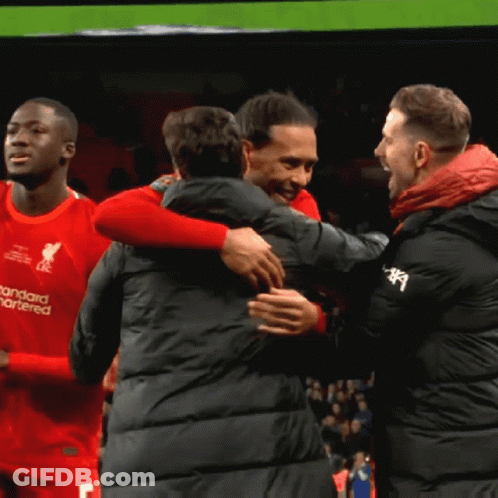 Man In Red Standard Chartered Shirt Hugging Another Man GIF
