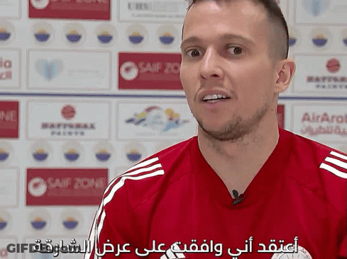 Man In Red Striped Shirt Talking In Front Of Airarab Sign GIF