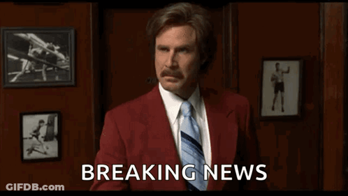Man In Red Suit And Tie Holding Breaking News GIF