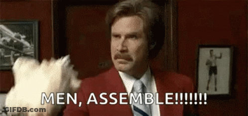 Man In Red Suit And Tie Holding Stuffed Animal Saying Men Assemble GIF