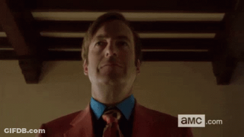 Man In Red Suit Holding Black Briefcase With AMC.com Sign GIF