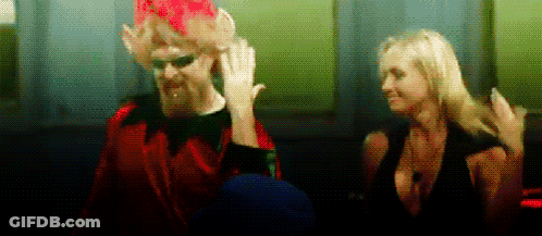 Man In Red Suit Next To Woman In Black Dress GIF