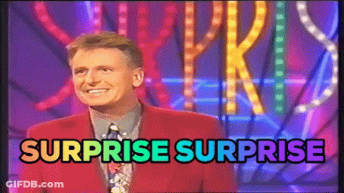 Man In Red Suit Standing In Front Of Surprise Surprise Sign GIF