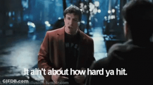 Man In Red Suit Talking To Another Man Says It Ain't About How Hard Ya Hit GIF