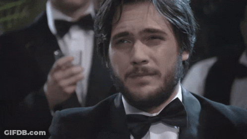 Man In Red Suit Talking To Man In Black Tuxedo GIF