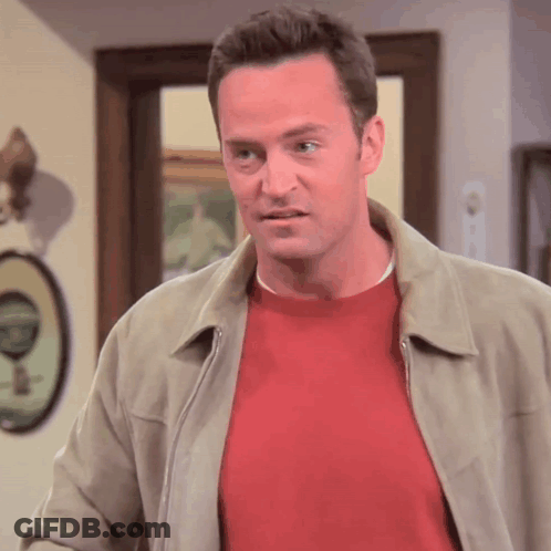 Man In Red Sweater And Tan Jacket Standing In Front Of Door GIF