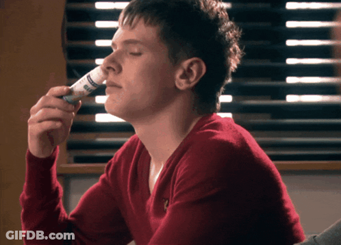 Man In Red Sweater Smelling Ear Spray GIF