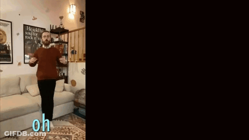 Man In Red Sweater Standing In Front Of Couch GIF